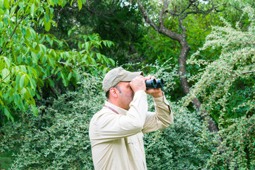 Forest ranger oversee with binoculars controlling the existence of forest fires.