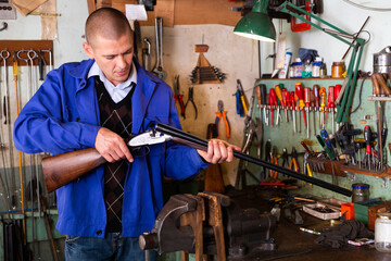 Gunsmith examines an automatic rifle before being repaired in a weapons workshop