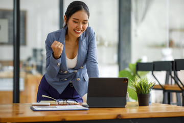 Excited executive receiving good news online sitting in a coffee shop, Business Success. Asian Businesswoman Celebrating Victory At Work. Free Space