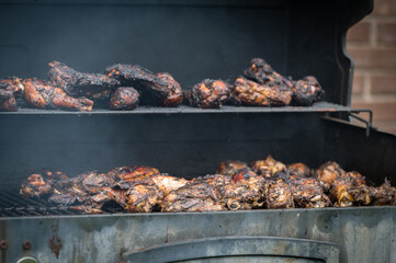 a barbecue grill cooks and grills chicken on a summer afternoon 