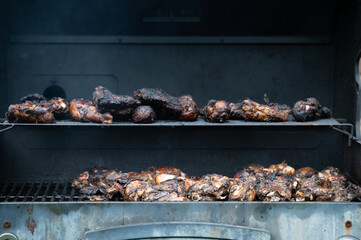 a barbecue grill cooks and grills chicken on a summer afternoon 