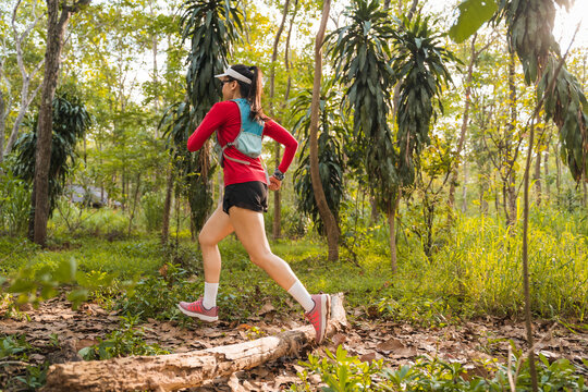 Rearview Of Adult Asian Woman Trail Runner With Running Vest Practices Trail Running In The Forest Park