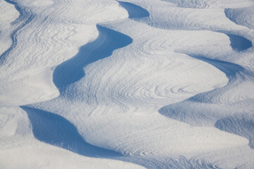 Beautiful winter background with snowy ground. Natural snow texture. Wind sculpted patterns on snow surface. Arctic, Polar region.