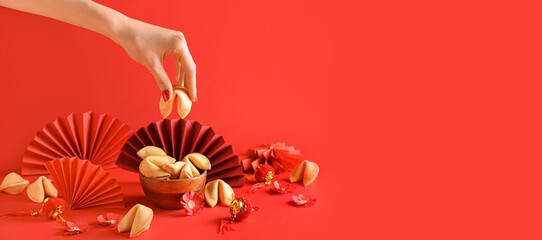 Female hand with Chinese fortune cookies in bowl on red background with space for text