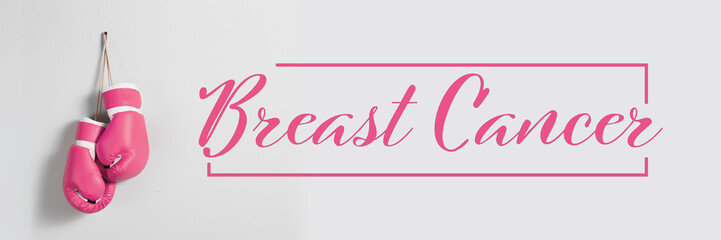 Pink boxing gloves and text BREAST CANCER on light background
