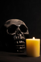 Old skull covered in dust and illuminated by candlelight in first plane with a black textured background and strong shadows