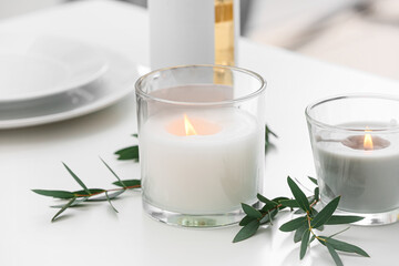 Holders with burning candles and branches on table, closeup