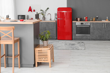 Interior of modern kitchen with red fridge, counters and pegboard