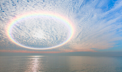 Beautiful calm sea landscape with amazing rounded rainbow in the white clouds