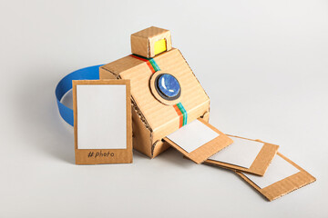 Cardboard photo camera with pictures on light background