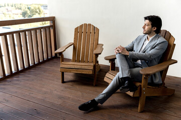 Young successful man sits thoughtfully in a light suit