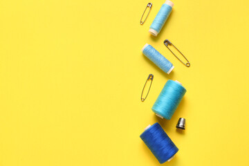 Thread spools and pins on yellow background