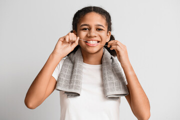 African-American teenage girl flossing teeth on light background