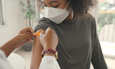 African american doctor is applying plaster to a child's shoulder after being vaccinated. 