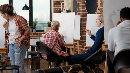 Senior man and woman attending community centre art class to develop drawing skills and learn to...