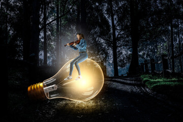 Girl plays on violin sitting on light bulb