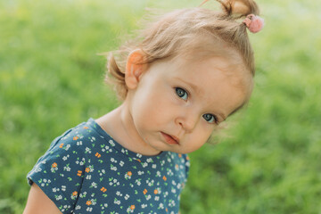 portrait of a cute little girl with blue eyes in a blue dress in the park
