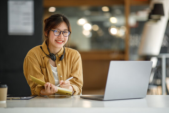 Student learning on laptop indoors- educational course or training, seminar, education online concept, Asian woman with modern laptop and headphones learning at home
