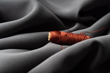 Reel with brown threads on gray silk fabric, macro, texture, close-up. Luxurious bright beautiful...