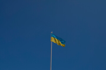 Ukrainian flag flutters in the wind against blue sky