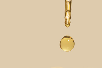 detail of gold pipette dropper with beauty serum on a beige background