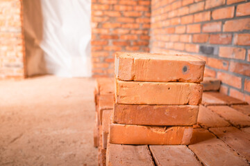 Red bricks stacked at a construction site, close-up. The bare brick walls of an unworthy house. The...