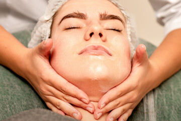 Obraz na płótnie Canvas Face massage. Beautiful caucasian young white woman having a facial massage with closed eyes in a spa salon