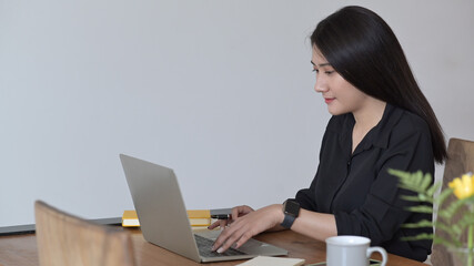 Pretty young woman searching information on laptop computer.
