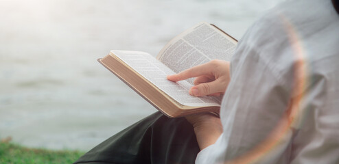 people sitting in the park reading the holy scriptures holding the bible in hand Concepts of Faith, Spirituality and Religion.