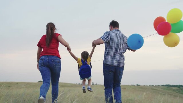 child kid runs with mother father with beautiful colorful balloons. happy family concept. group people running across field with helium colored balloons. happy family running green field together.
