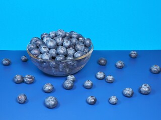 Fresh, ripe blueberries in a glass container. Blueberries on a blue background. Healthy dessert