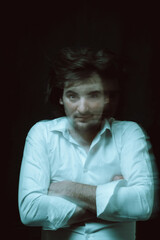 schizophrenic portrait of psychopathic man with mental disorders in white shirt on dark background