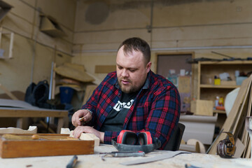 carpenter in a plaid shirt working with wood in the workshop