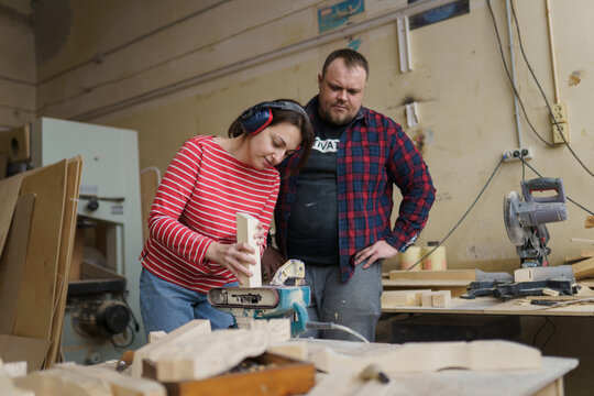 a man and a woman work in a carpentry shop