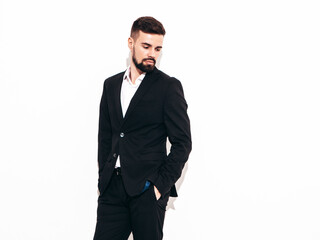 Portrait of handsome confident stylish hipster lambersexual model. Sexy modern man dressed in elegant black suit. Fashion male posing in studio near white wall. Isolated