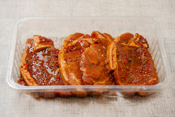 Fresh pork chops in Korean style marinade with spicy sous and herbs. Summer barbeque product in a plastic tray. Meat industry. Orient inspired flavor.