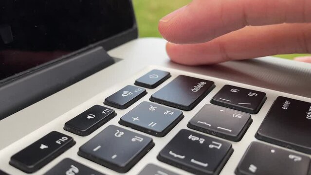 Typing on keyboard. Male hand finger press "delete" key button repeatedly on English - Thai laptop keyboard. Digital nomad professional hand on laptop close up - technology concept