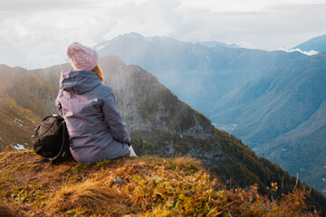 Fototapeta premium female tourist with a backpack enjoys the sunset at the top mountain