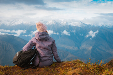 female tourist with a backpack enjoys the sunset at the top mountain