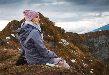 female tourist with a backpack enjoys the sunset at the top mountain