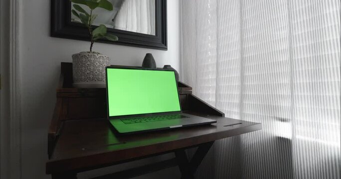 Home office in quiet and calm room with modern desk. Steadicam slowly pushes in to Close Up shot of green screen laptop for chroma key.