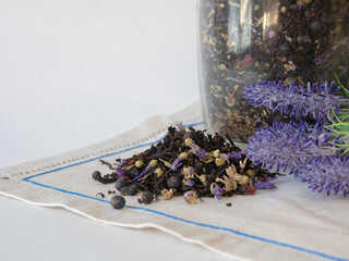 Herbal tea with blue dried flowers is scattered on the table in front of a glass jar of lavender...