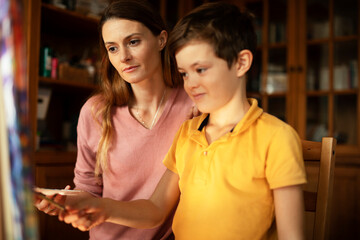 Mother and son painting at home. Little boy drawing with mom in living room.