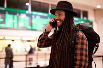 Handsome guy at railway station waiting for the train. Young man waiting to board a train. Urban guy using the phone