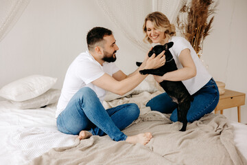 couple playing with French Bulldog in bed