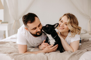 portrait of beautiful couple and french dog in bed