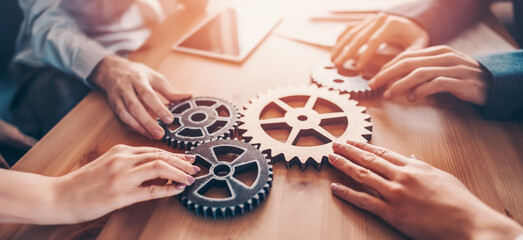Group of people working in the office while putting together cogwheels. - obrazy, fototapety, plakaty