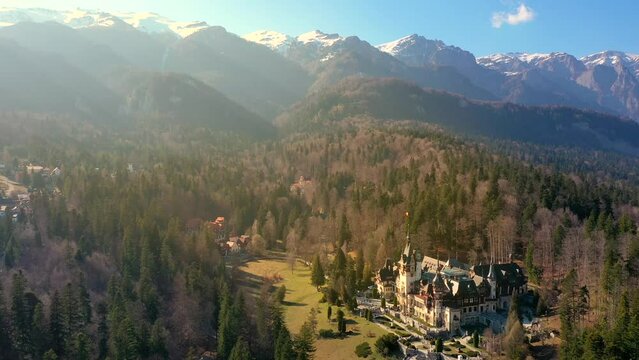 Aerial view of Peles Castle with Bucegi Mountains in background 4k video landmark of Romania