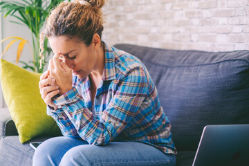 Anxiety and stress disease life concept. Unhappy and worried woman touching his head at home sitting on the sofa. Lonely female people with sadness alone sitting on the sofa. Flu coronavirus symptoms