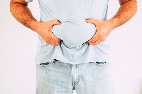 Unrecognizable man hlding his fat belly in white background. Studio shot for diet and fitness concept lifestyle. Weight loss nad body unhappy postivity people. Adult male and fat healthy